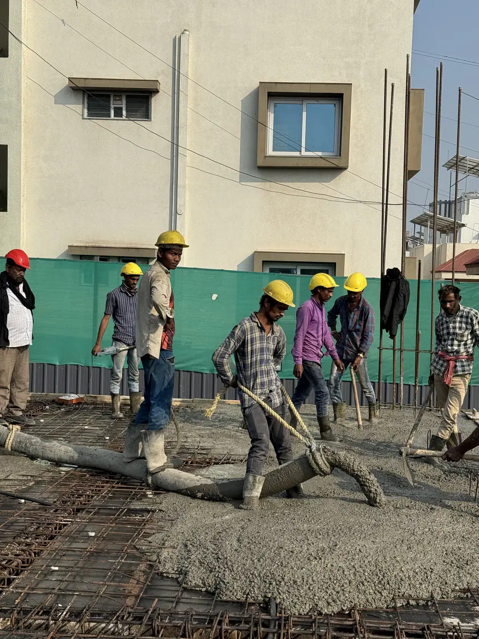 Site team pouring and levelling concrete on a slab at Shreeji Avenue